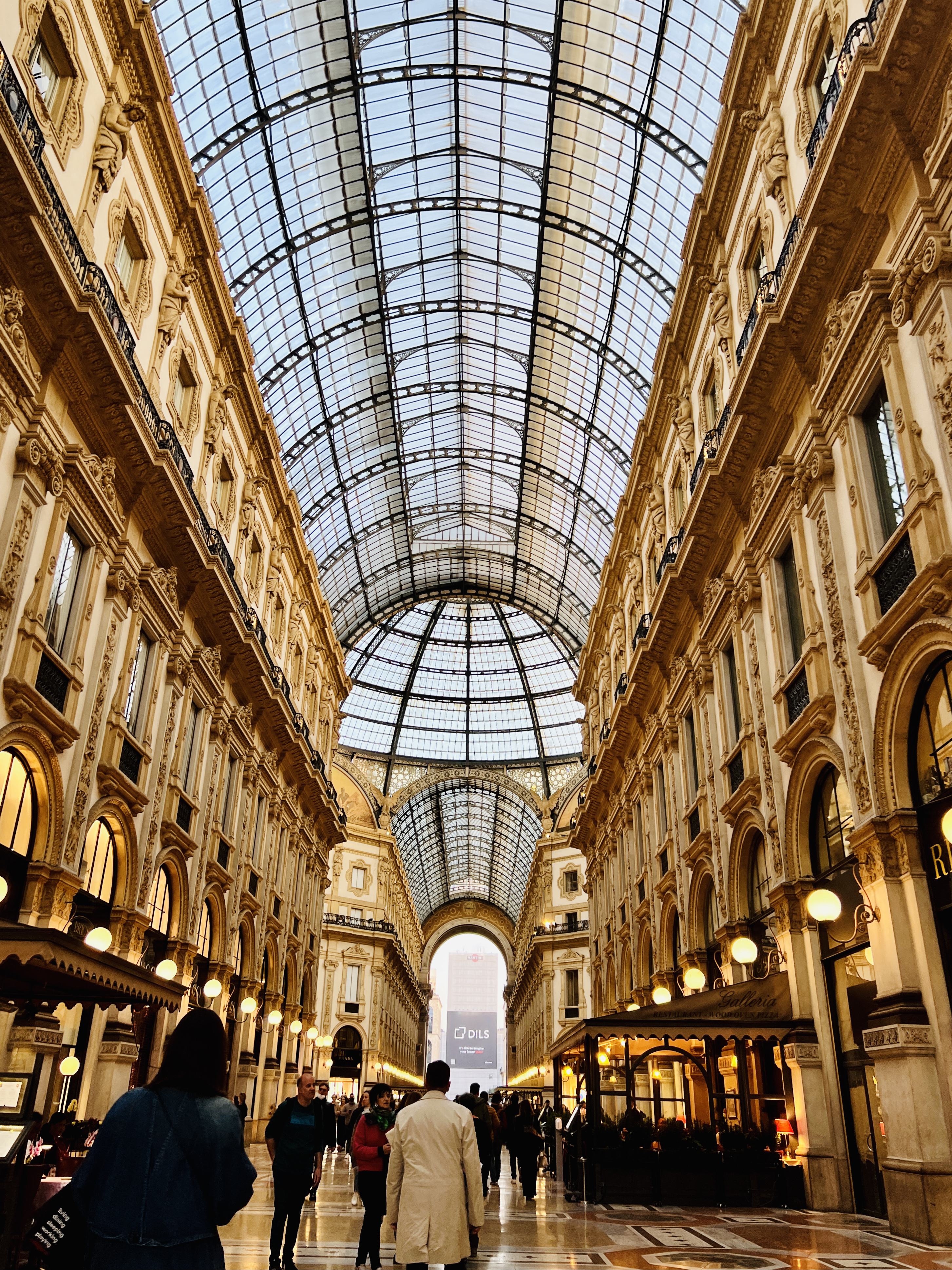walkway of Galleria Vittorio Emmanuele II in Milan, Northern Italy with a glass roof, lanterns, and golden walls