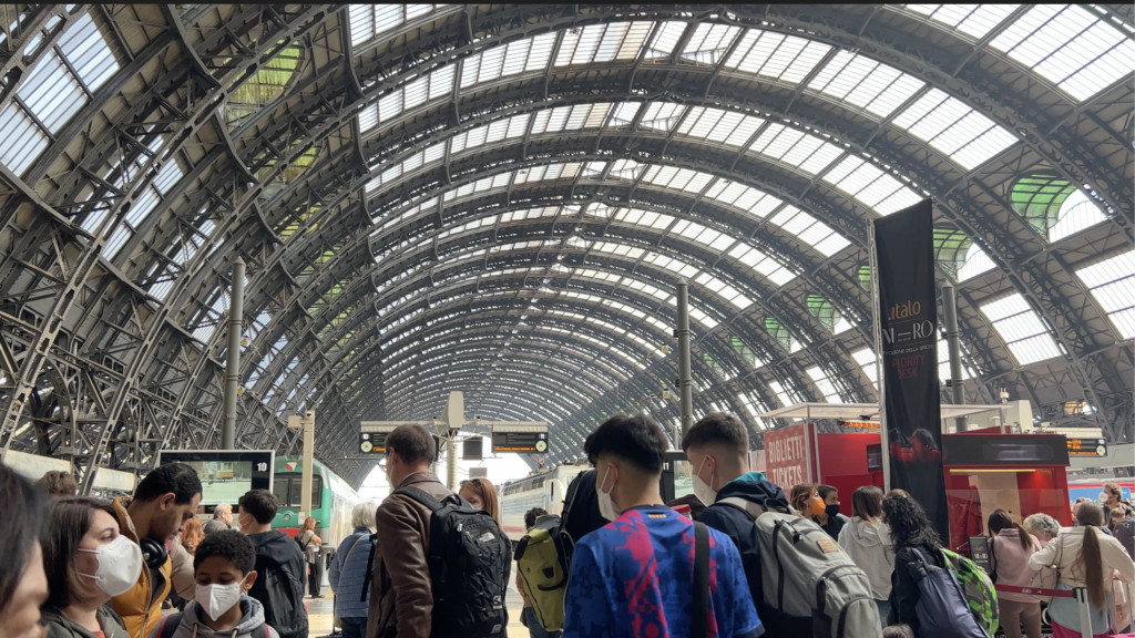 travelers under the domed roof of Milano Centrale, Milan