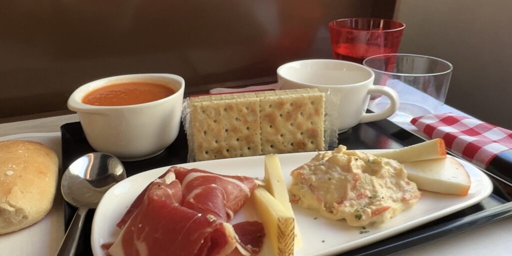 Spanish snacks including tomato soup, ham, potatoes, cheese, crackers, and bread